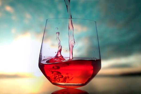 Afbeelding van glas rode wijn en zonsondergang op achtergrond